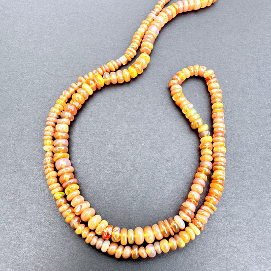 Opal with orange and yellow beads on a gray background.