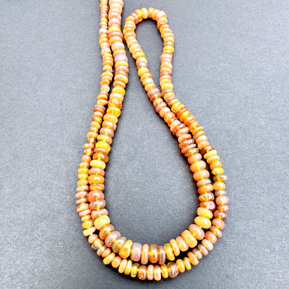 Close up of Opal with orange and yellow beads on a gray background.