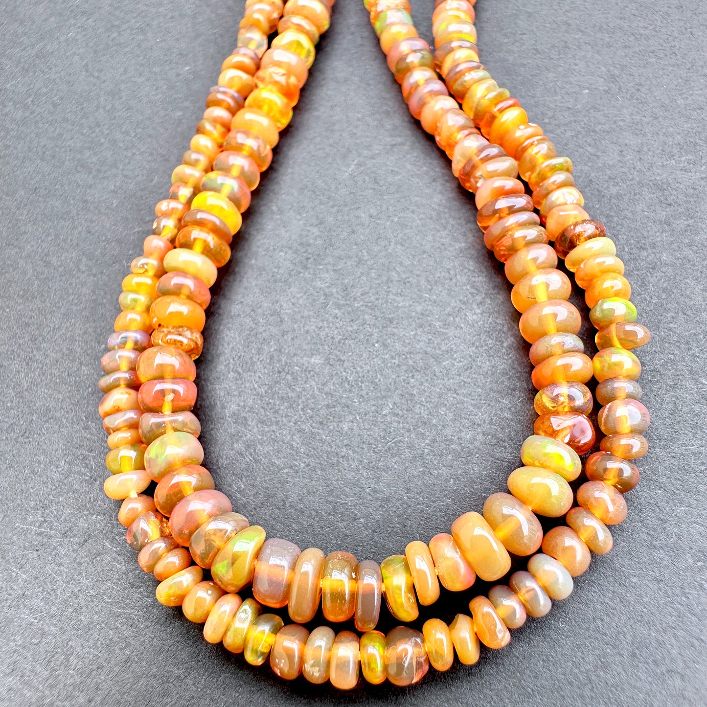 Opal with orange and yellow beads on a gray background.