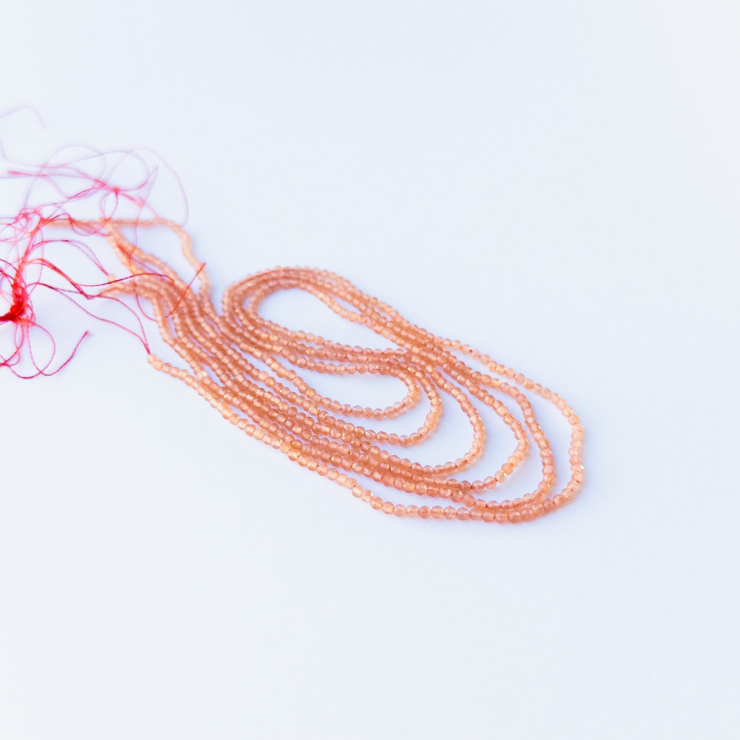 delicate strands of Orange Chalcedony beads, showcasing their faceted rondelle design and sparkle