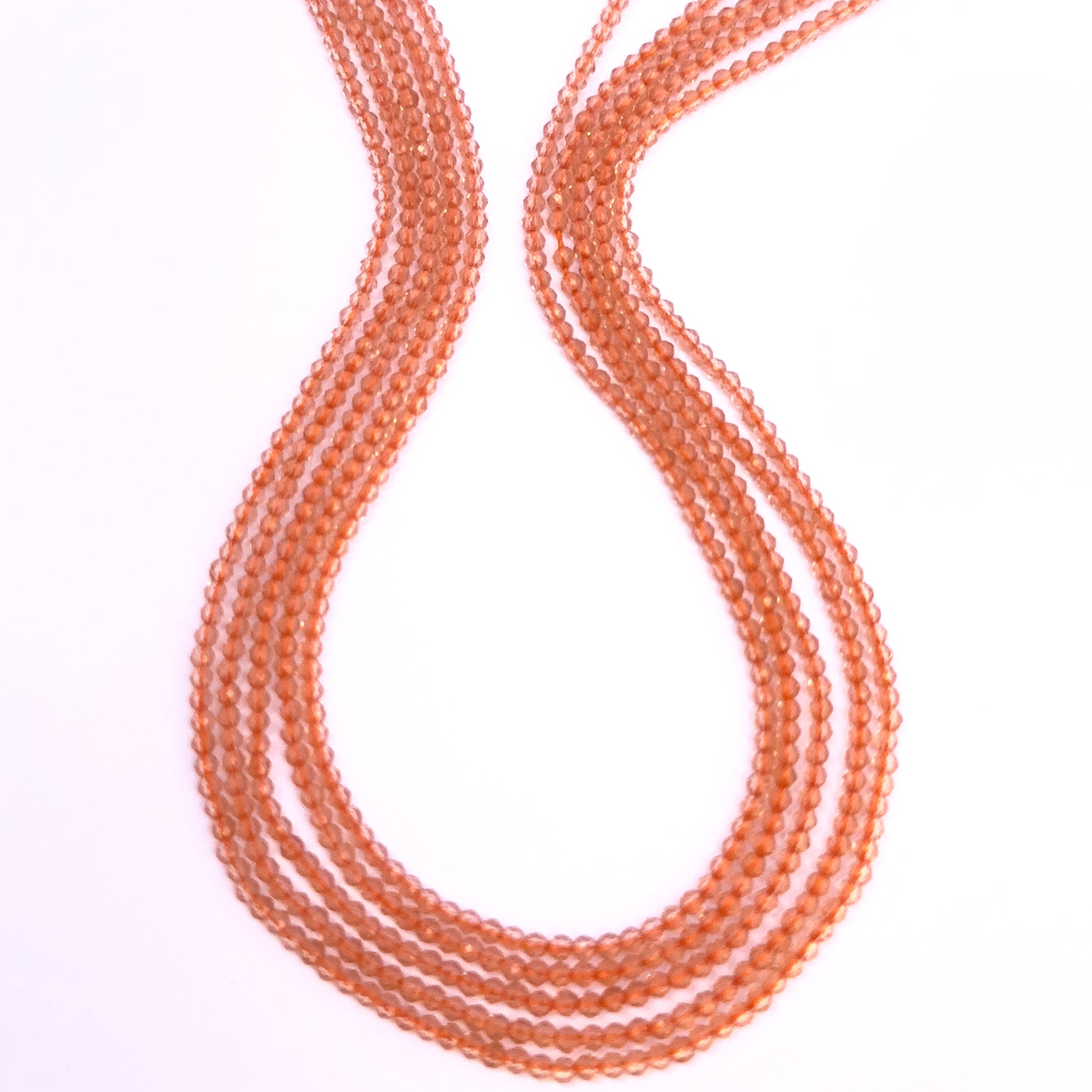 Close-up of Orange Quartz gemstone beads showing faceted rondelle cut and sparkle.