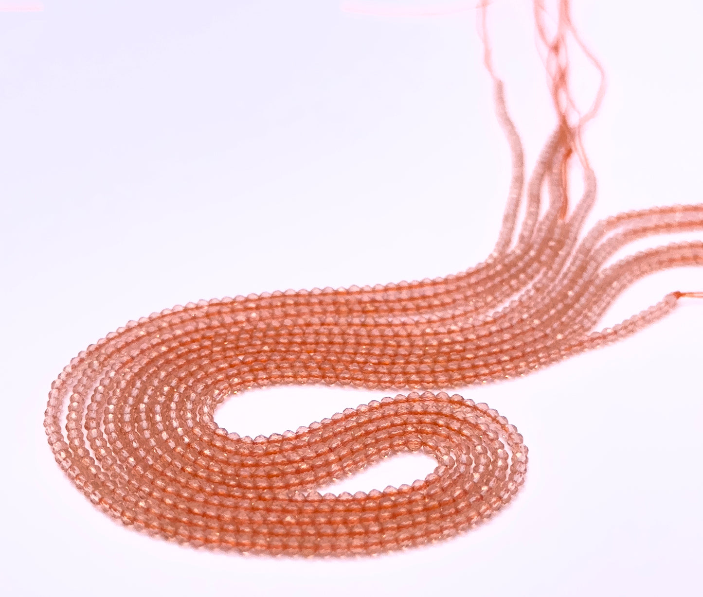 Natural Orange Quartz stone beads arranged in strands with bright shimmering hues.