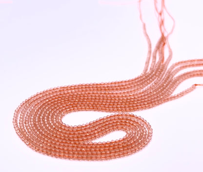 Natural Orange Quartz stone beads arranged in strands with bright shimmering hues.