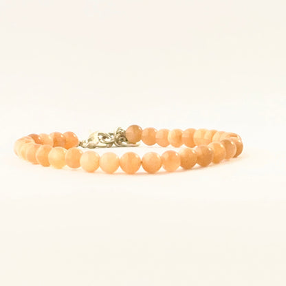 Single‑strand peach moonstone bracelet with adjustable closure.
