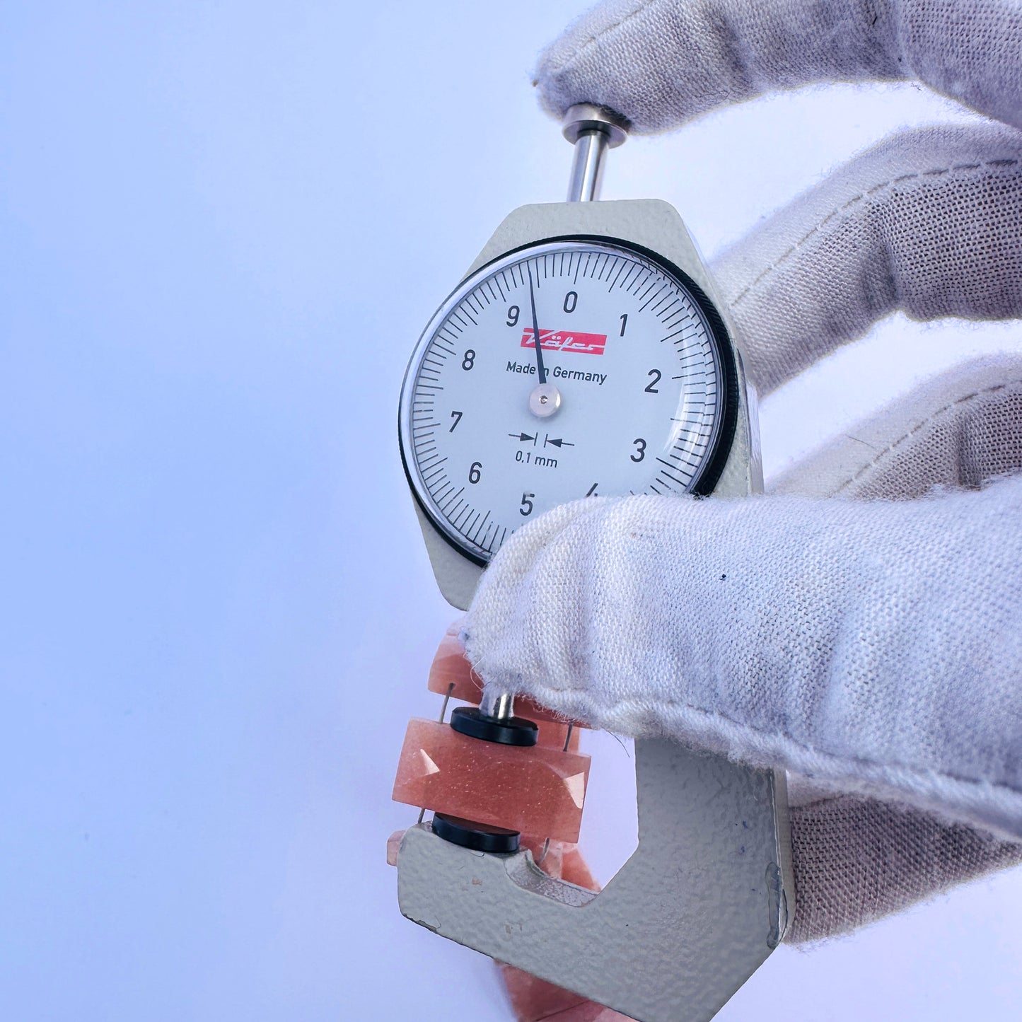 A dial gauge measures the Peach Moonstone faceted rectangle 20×9–9.5mm gemstone.