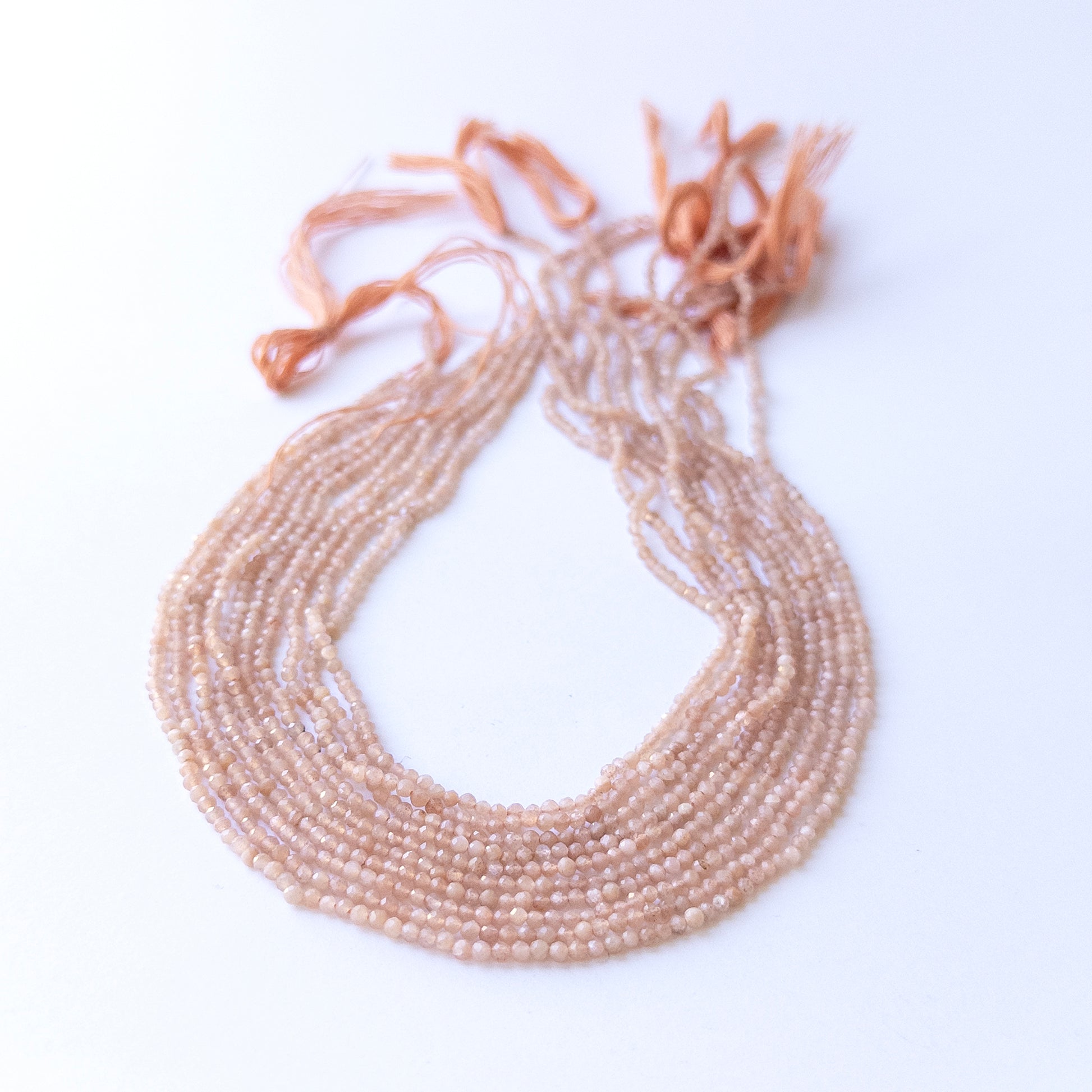 Genuine Peach Moonstone gemstone beads displaying soft peach tones, polished facets, and a neatly arranged 33cm strand for jewellery design.