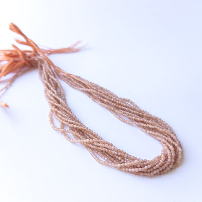 Close‑up of authentic Peach Moonstone faceted rondelle beads showing their shimmer, clarity, and consistent 2.4mm sizing.