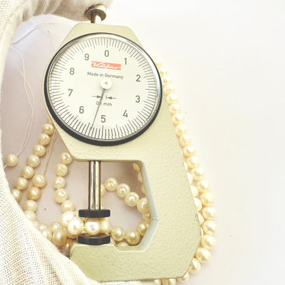 A dial gauge measures the pearl round 5.4-5.6mm gemstone.