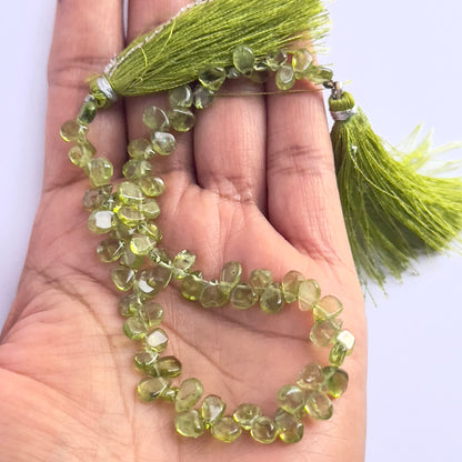 A person holds delicate strands of Peridot beads, showcasing their smooth design.