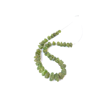 High‑quality Peridot drilled rough stones aligned on a 20cm strand for jewellery crafting projects.