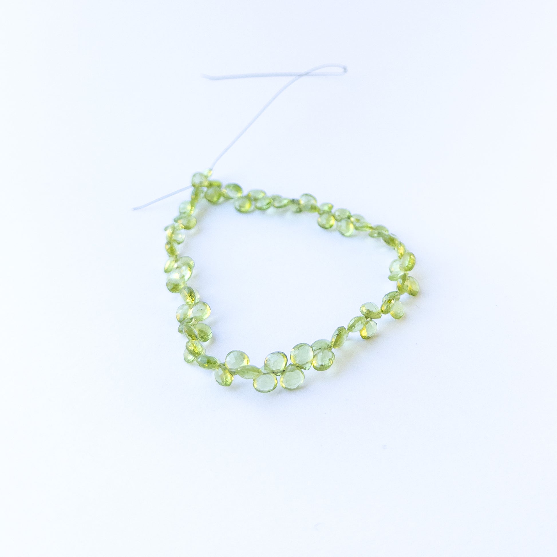 Peridot faceted briolette beads in 5.5–6mm size on a 25cm strand, showcasing genuine gemstone sparkle.