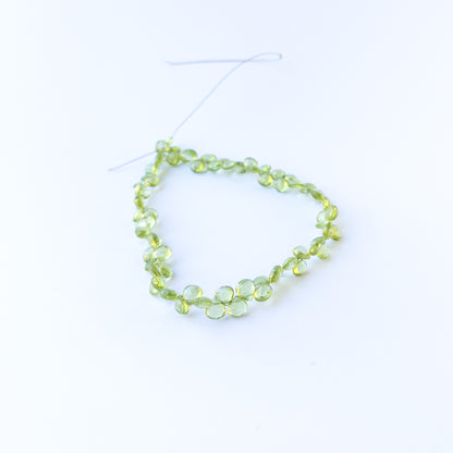 Peridot faceted briolette beads in 5.5–6mm size on a 25cm strand, showcasing genuine gemstone sparkle.