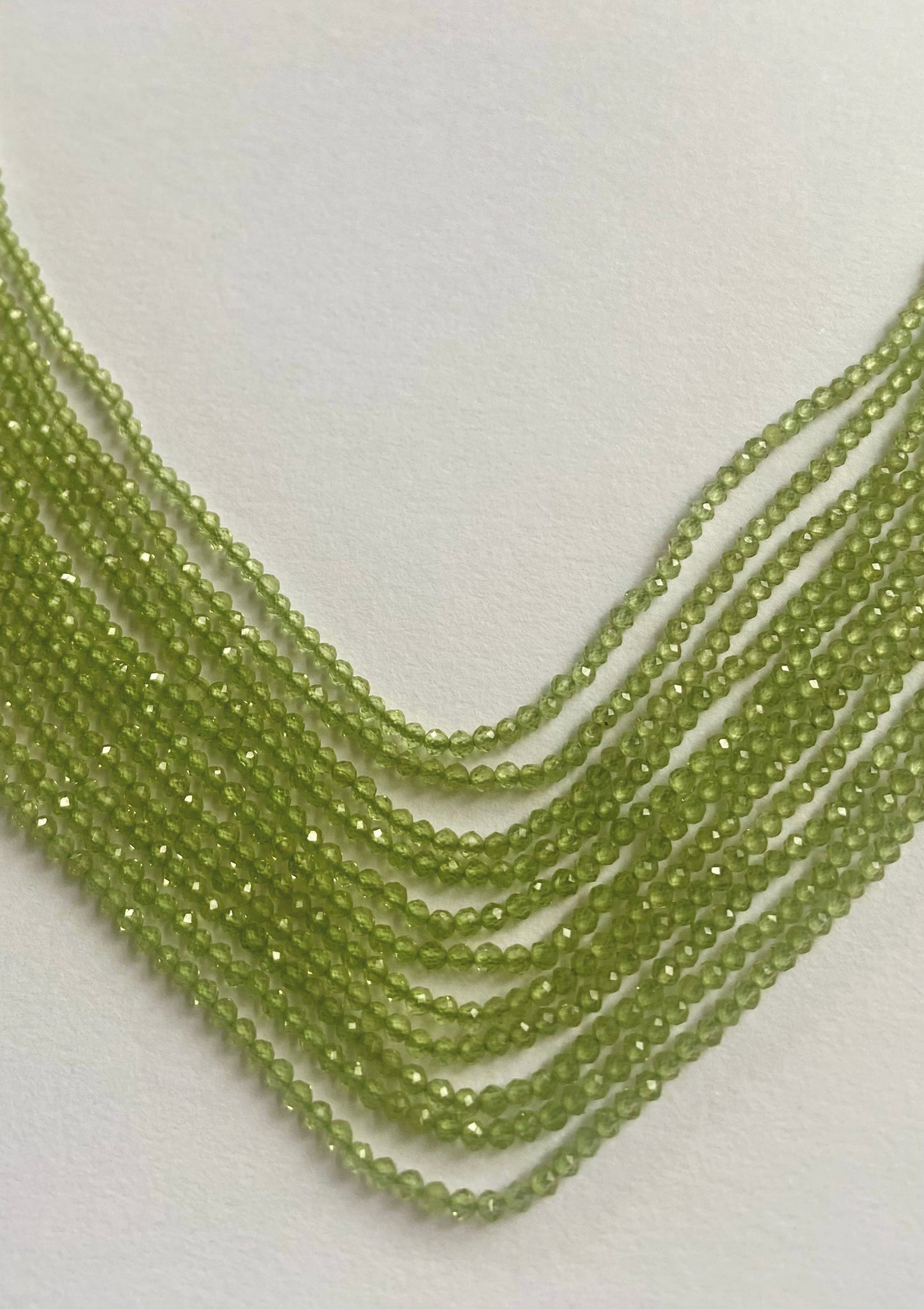 Close-up of Peridot gems in a faceted rondelle shape, arranged in soft gradients.
