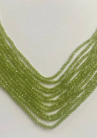 Close-up of Peridot gems in a faceted rondelle shape, arranged in soft gradients.
