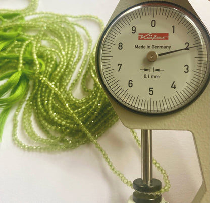 A dial gauge measures the Peridot faceted rondelle 2.2mm gemstone.