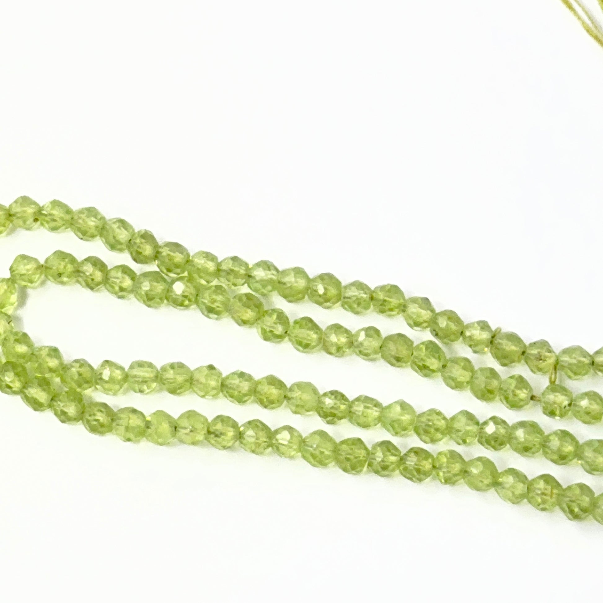 Close view of polished Peridot faceted rondelles arranged on a 15cm strand for handmade jewellery components.