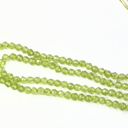 Close view of polished Peridot faceted rondelles arranged on a 15cm strand for handmade jewellery components.