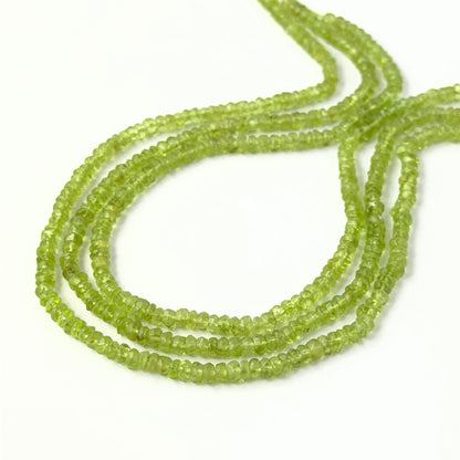 Genuine Peridot faceted rondelles arranged in a neat strand, showcasing their vivid colour and polished finish.