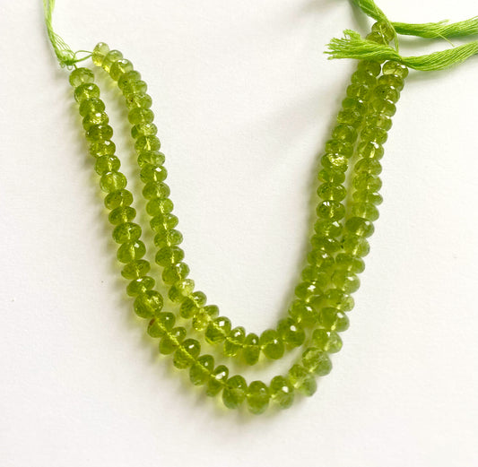 Vibrant green Peridot beads arranged in a tight strand showing their sharp facet pattern. Close-up of sparkling Peridot rondelle beads showcasing precision cutting and crystal clarity.