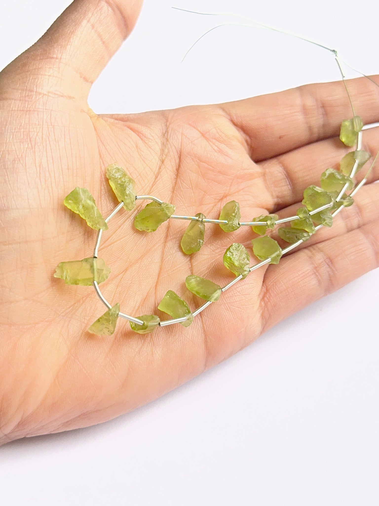 A person holds delicate strands of amethyst faceted beads, showcasing their smooth design.