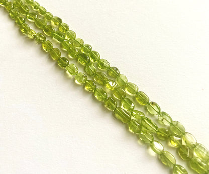 Peridot smooth oval beads in vibrant green tones, arranged on a 34cm strand.