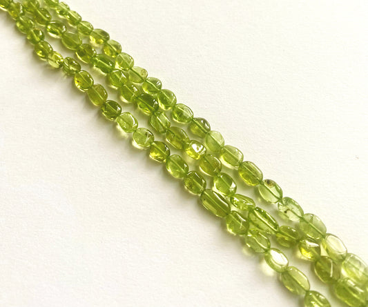 Peridot smooth oval beads in vibrant green tones, arranged on a 34cm strand.