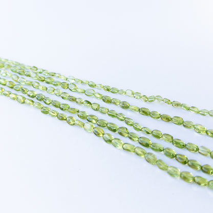 Peridot smooth oval beads displaying soft translucency and vibrant green tones.