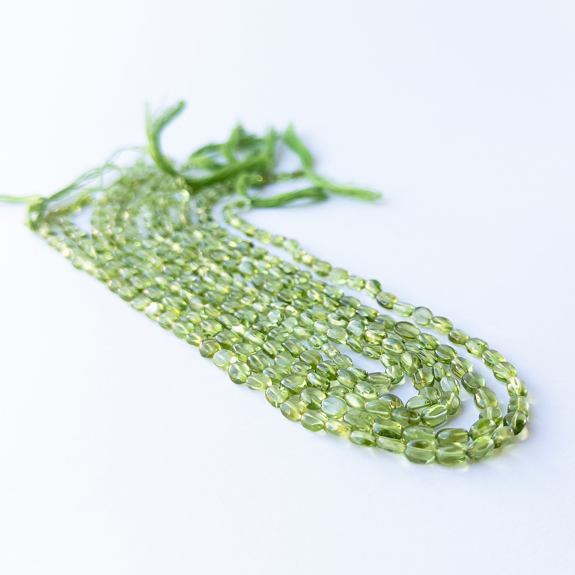 Close‑up of genuine Peridot smooth oval beads showing their fresh green colour and shine.