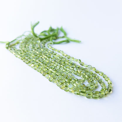 Close‑up of genuine Peridot smooth oval beads showing their fresh green colour and shine.