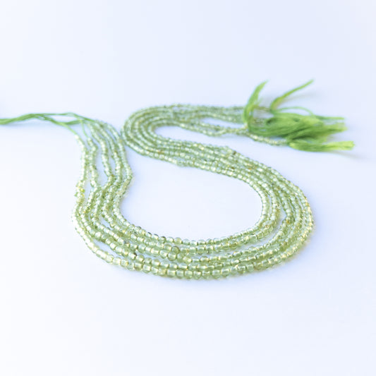 Peridot smooth round beads in 2.7–3mm size arranged in a strand, showing bright green tones for handmade jewellery components.