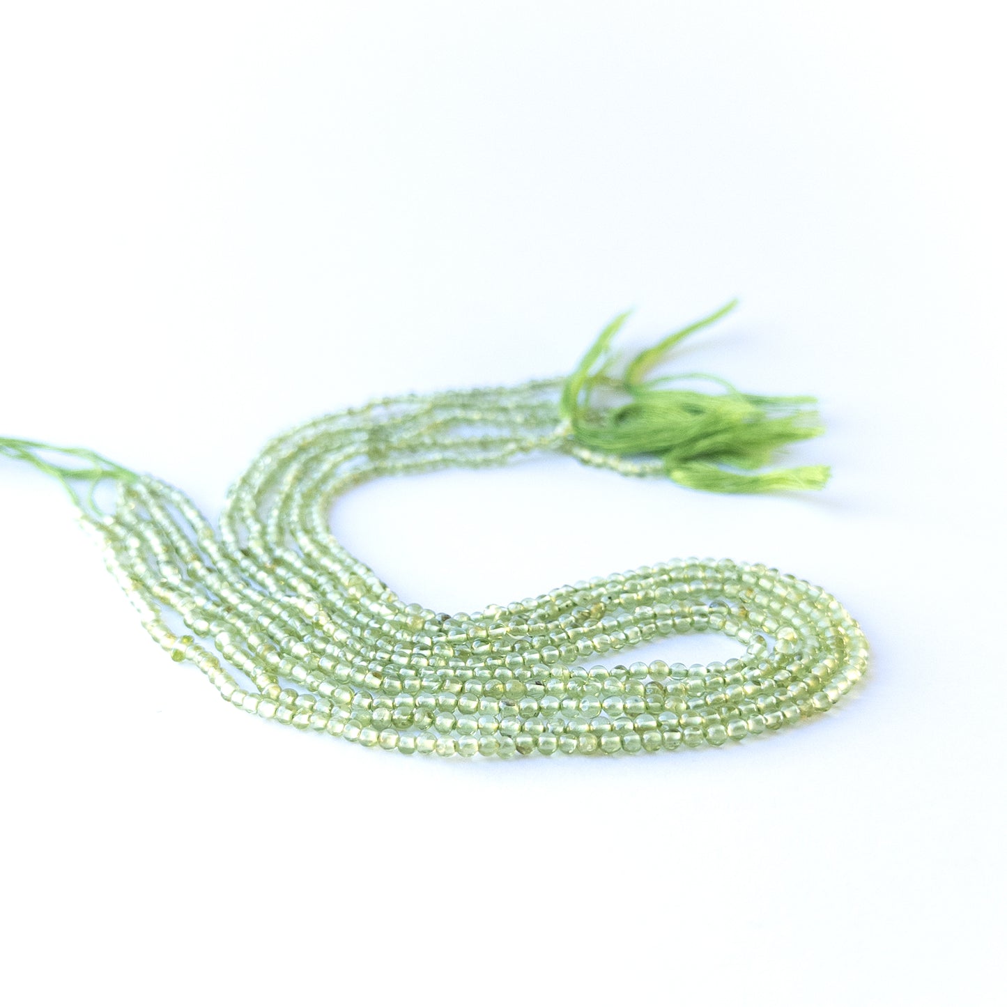 Close‑up of genuine peridot smooth round gemstone beads with natural shine for DIY jewellery making.