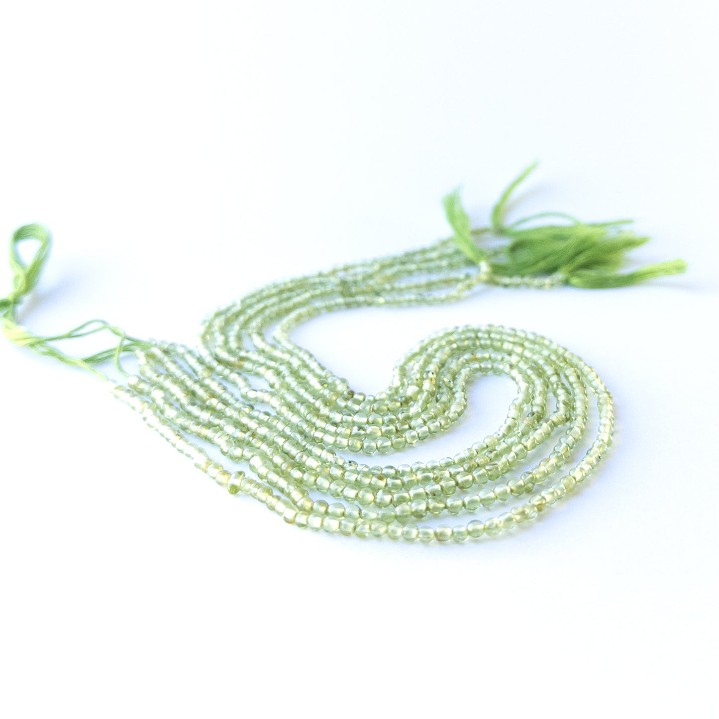 Authentic peridot stone beads in polished smooth round cuts showing fresh green colour for jewellery design work.