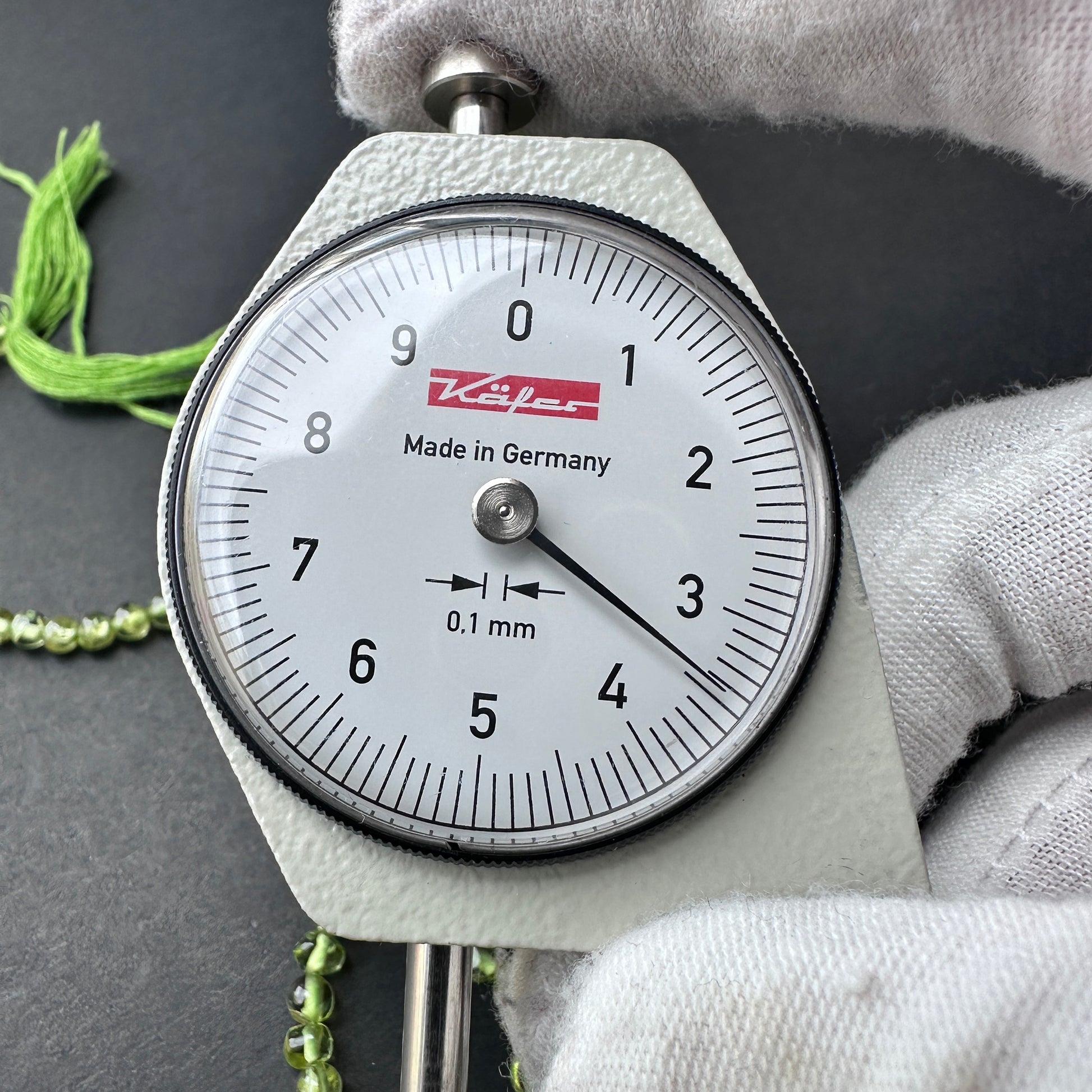 A dial gauge measures the Peridot smooth round 3.5mm gemstone.