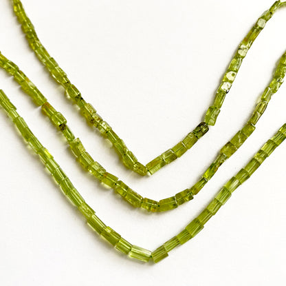Macro shot capturing the translucent green glow of Peridot tube cut beads, 4.5–6mm in length.