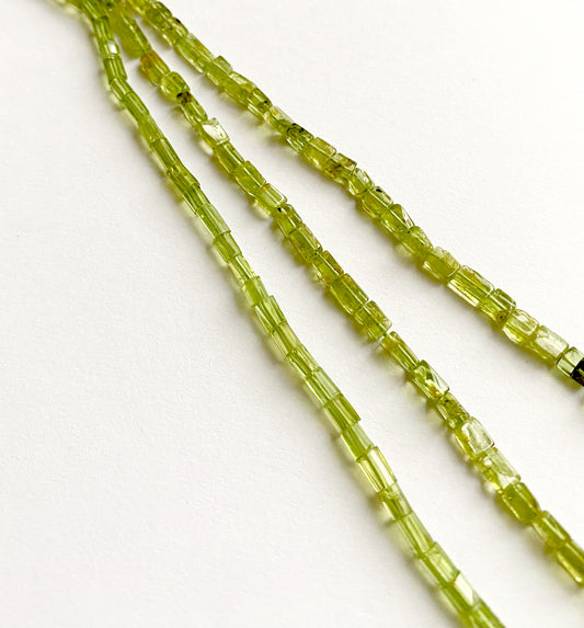 Peridot tube beads arranged in a 34cm strand, showcasing their vibrant green shine and uniform cut.