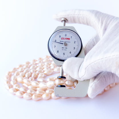 A dial gauge measures the Pink Freshwater Pearls baroque oval 7.5–8mm bead size gemstone.