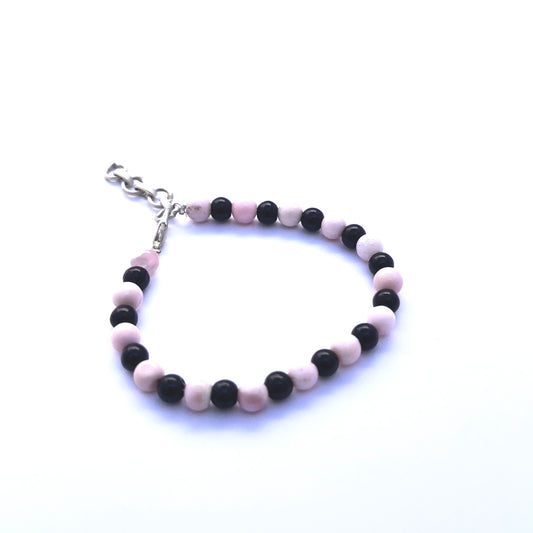 Close-up of polished pink and black stone beads arranged in a stylish bracelet.