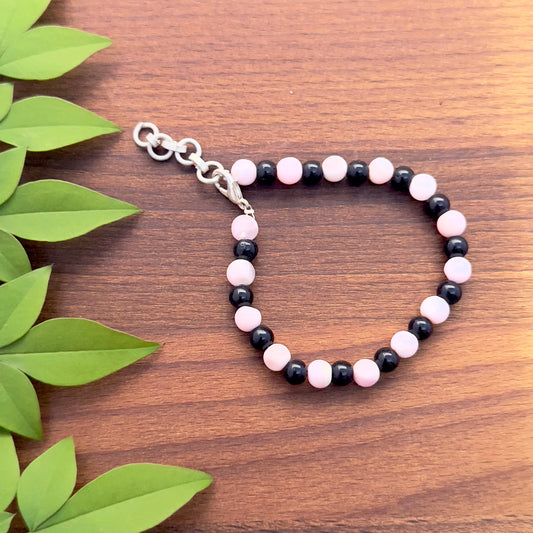 Pink opal and black gemstone bracelet with 6.5mm smooth round beads and adjustable lobster clasp.