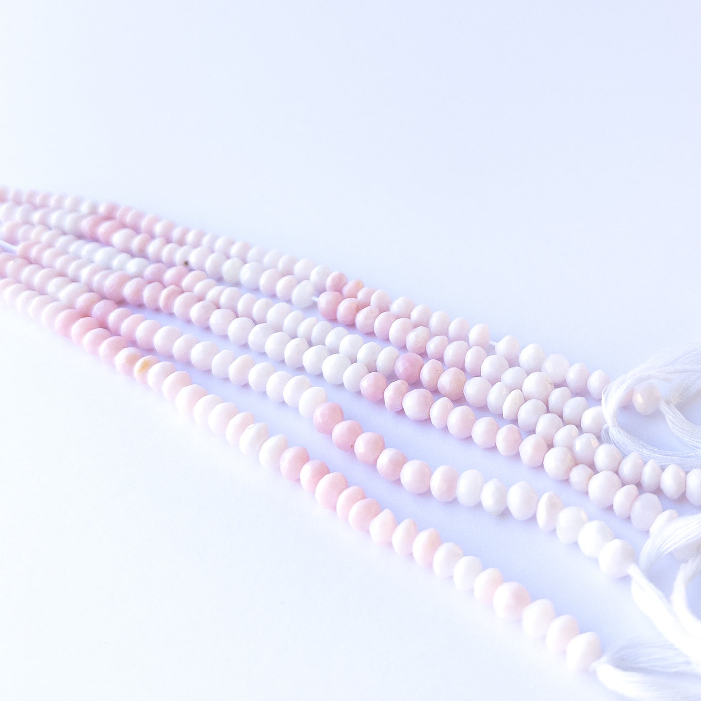Handmade jewellery components featuring natural pink opal faceted rondelles with soft tones and polished sparkle.