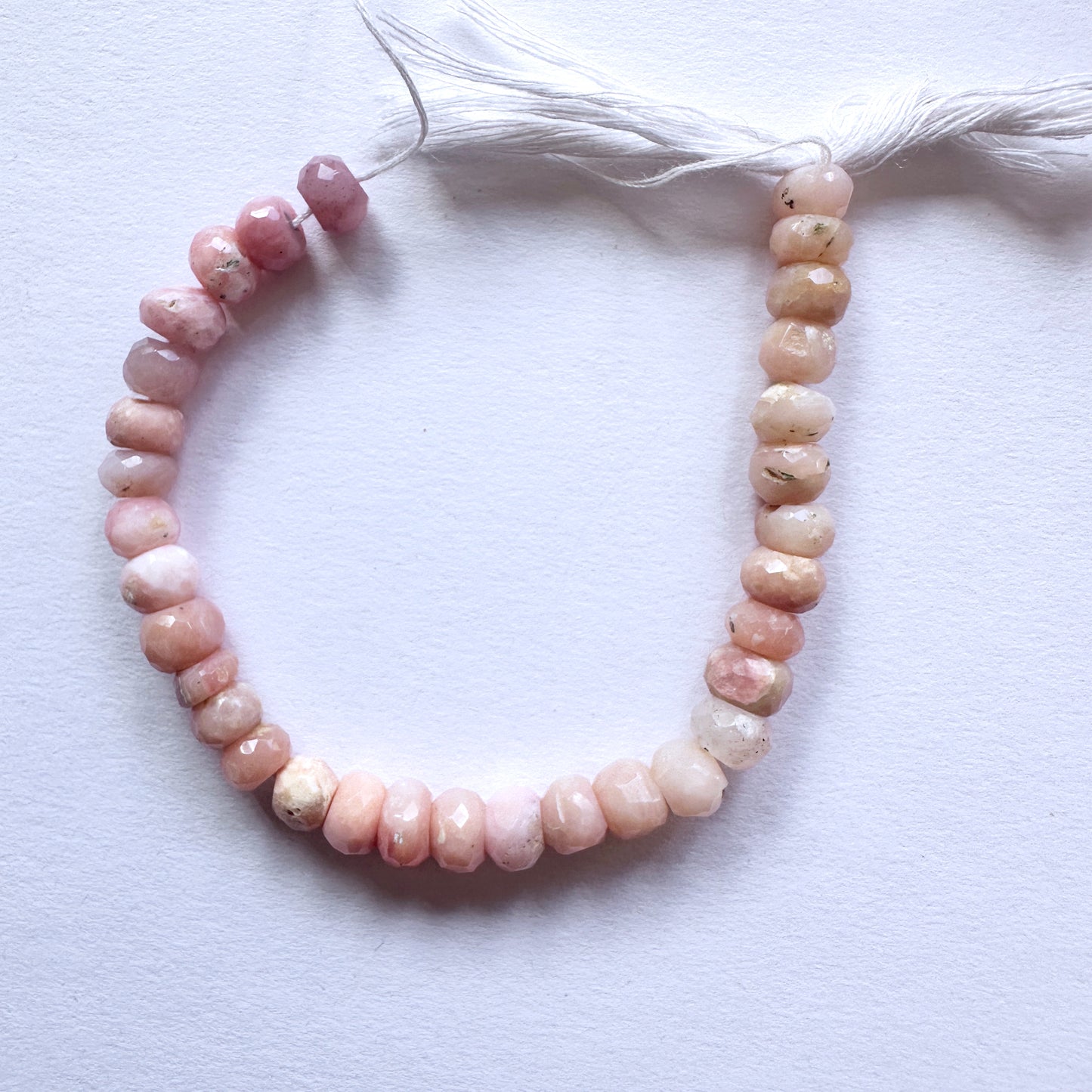 Natural gemstone beads with soft pink hues and sparkling facets, arranged on a 14cm strand.