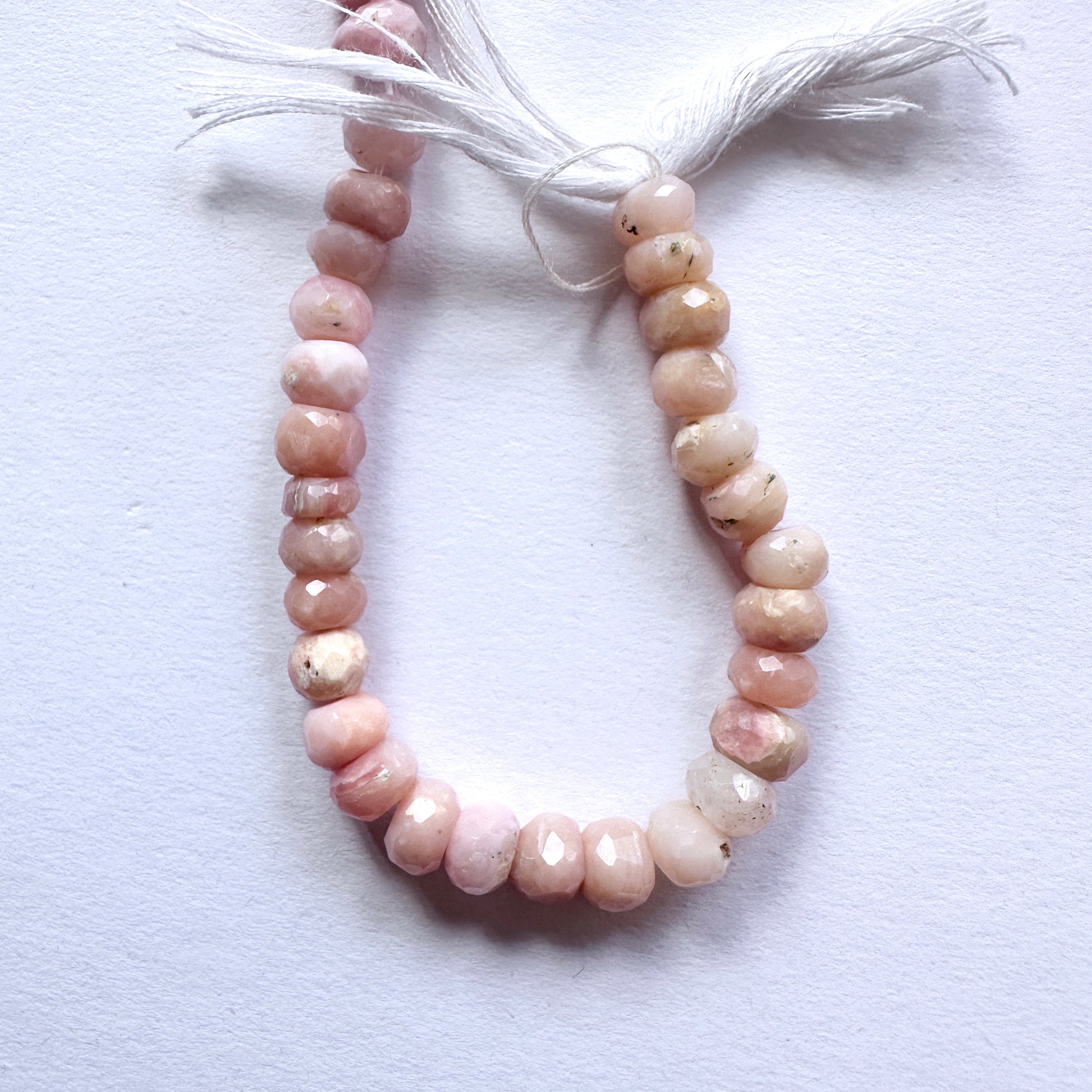 Close-up of Pink Opal beads showcasing their faceted cut and delicate blush colour.