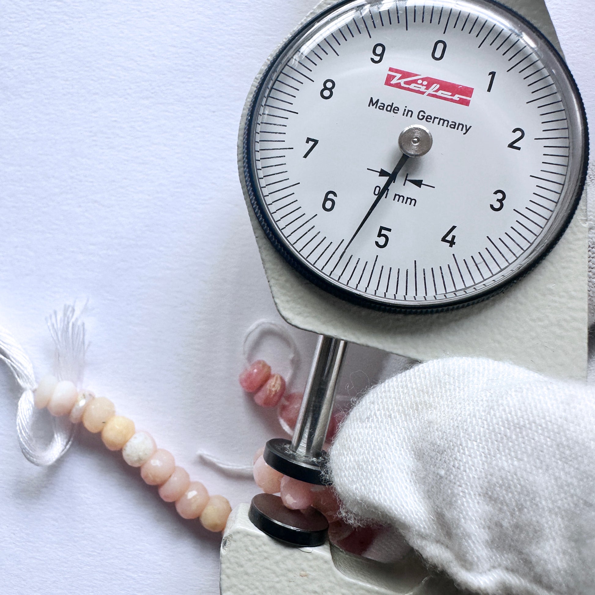 A dial gauge measures the Pink Opal faceted rondelle gemstone.