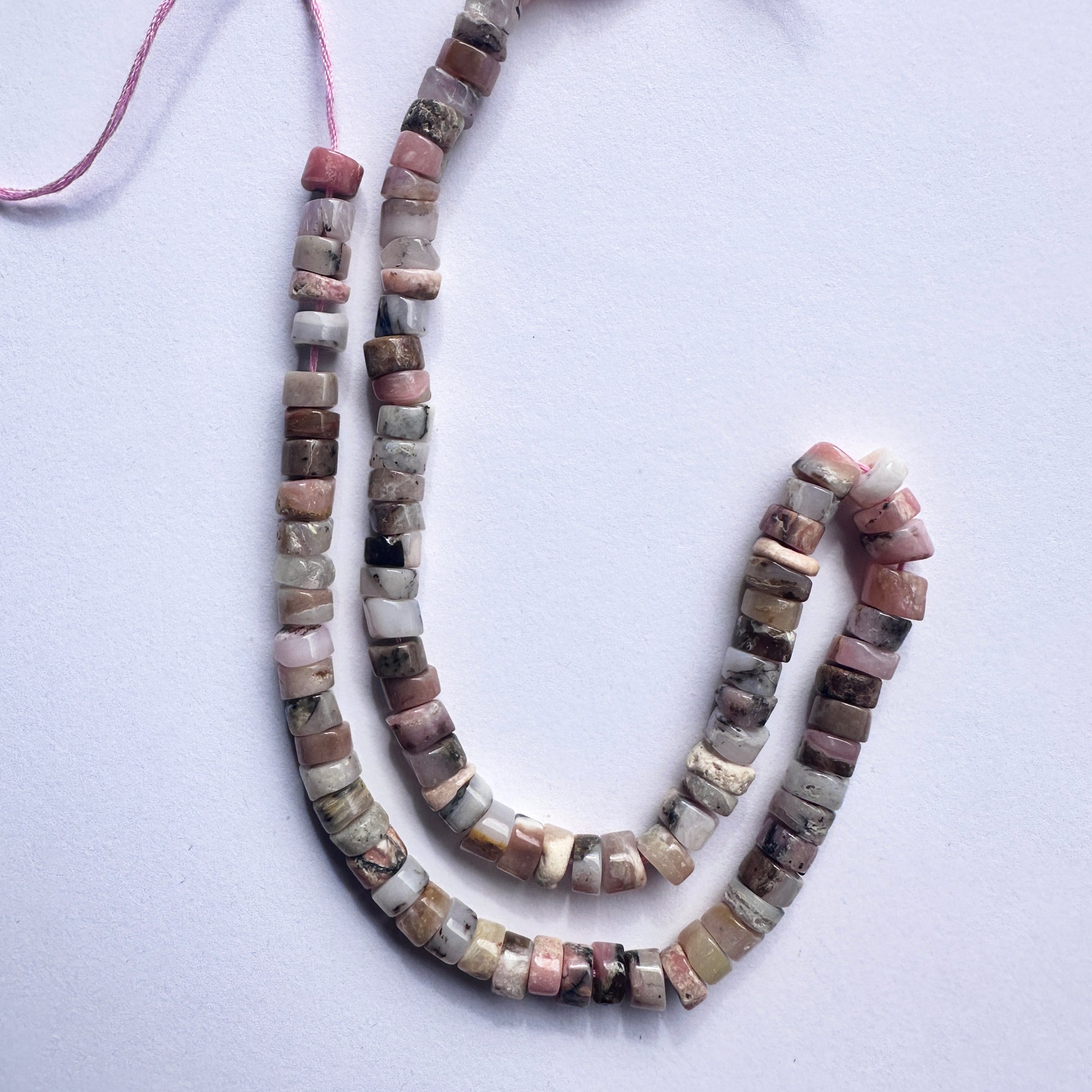 Close-up of Pink Opal beads showcasing their gentle colour and sleek disc shape.