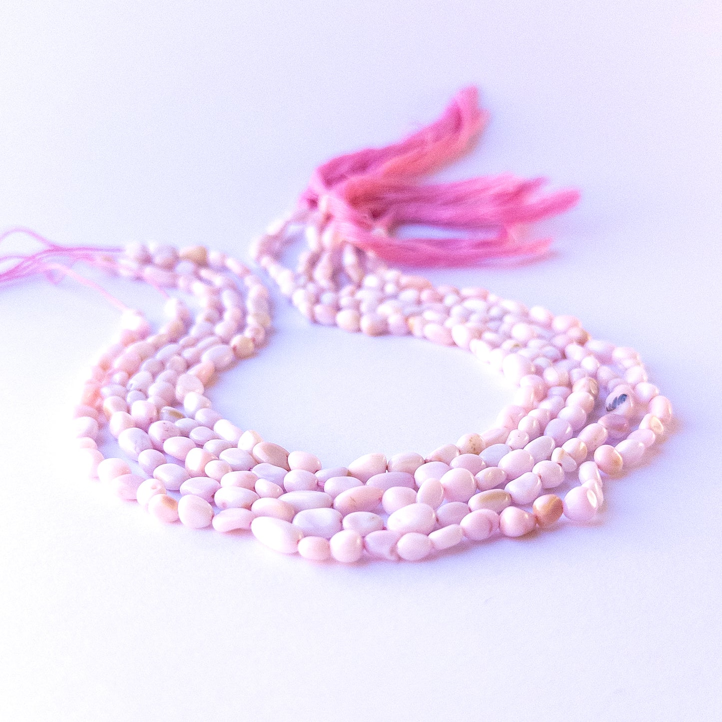 Close‑up of genuine pink opal smooth tumble gemstone beads with natural shine for DIY jewellery making.