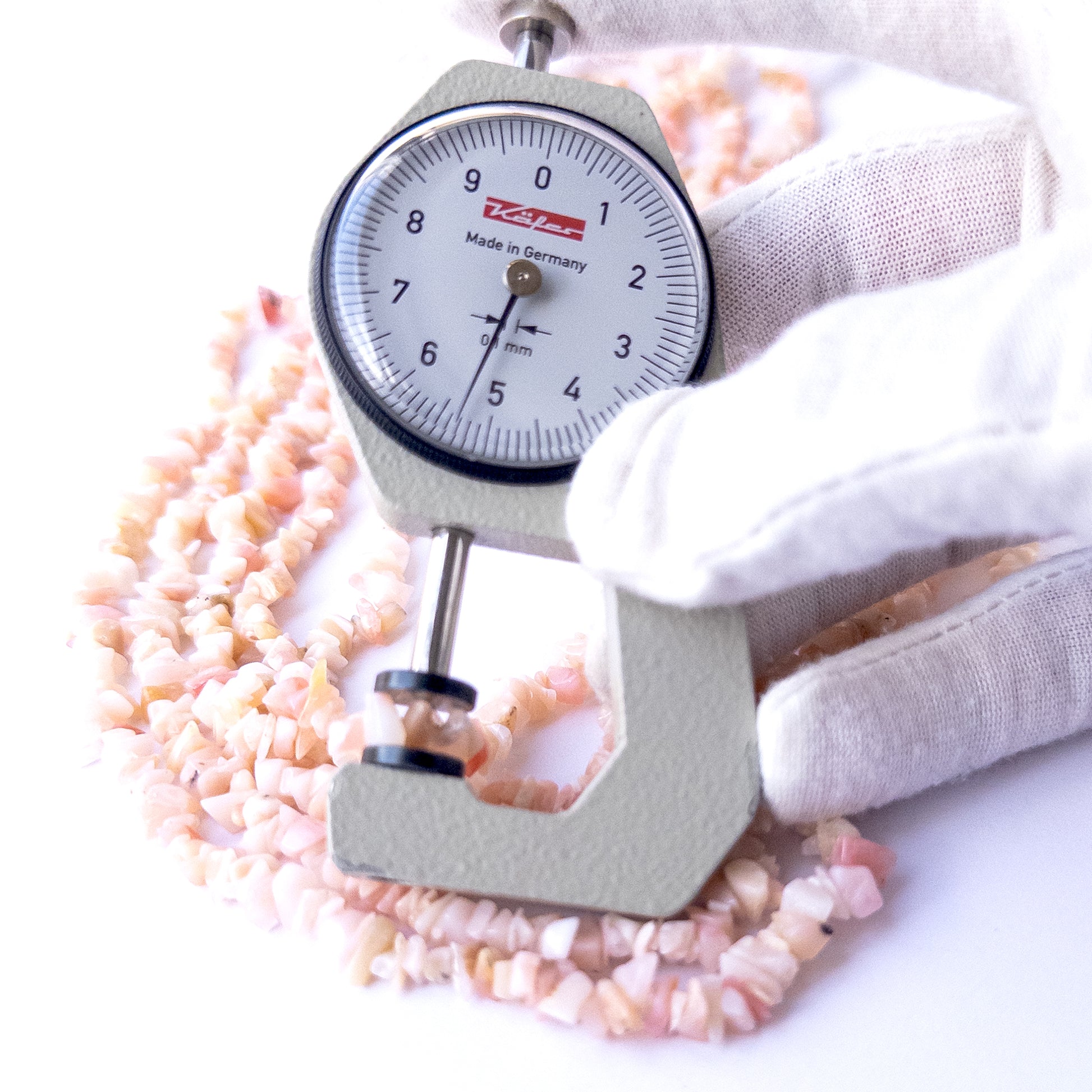 A dial gauge measures the Pink Peruvian Opal chip 4–5mm gemstone.