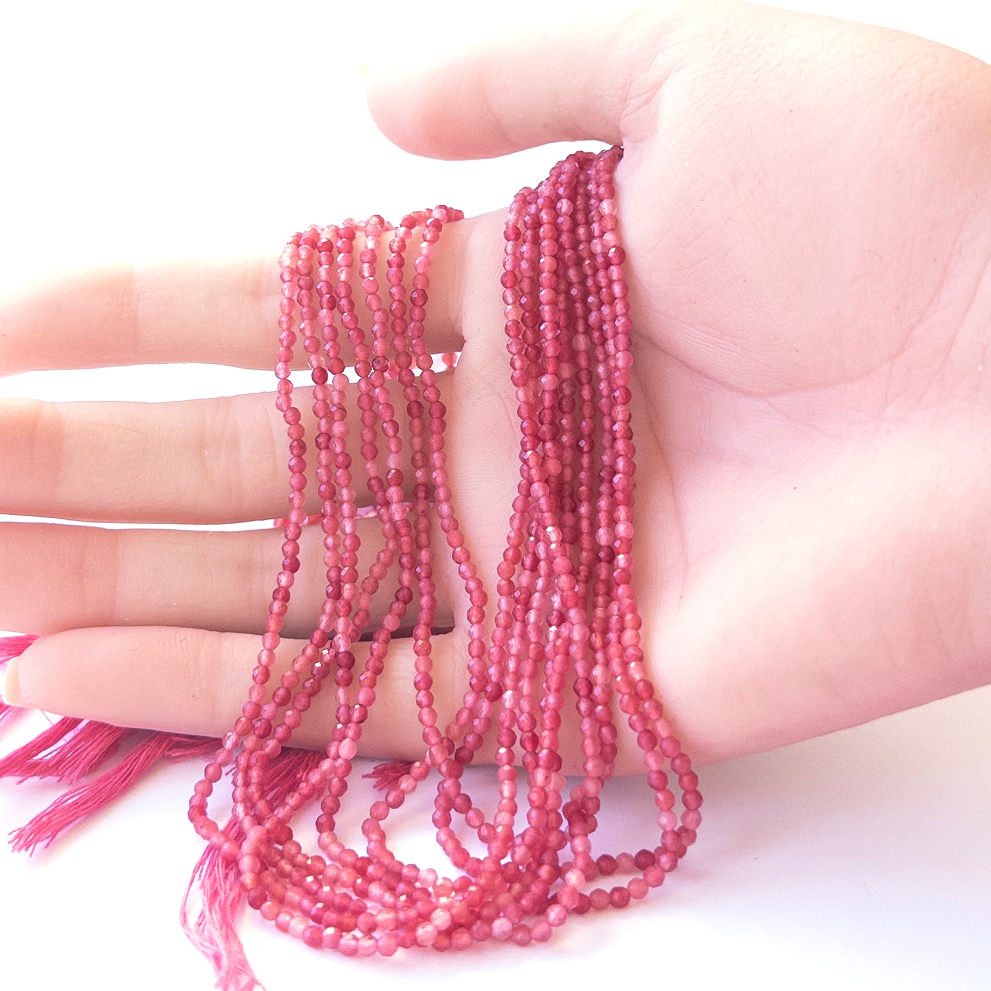 A person holds delicate strands of Amethyst beads, showcasing their faceted rondelle design.