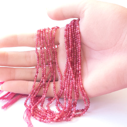 A person holds delicate strands of Amethyst beads, showcasing their faceted rondelle design.