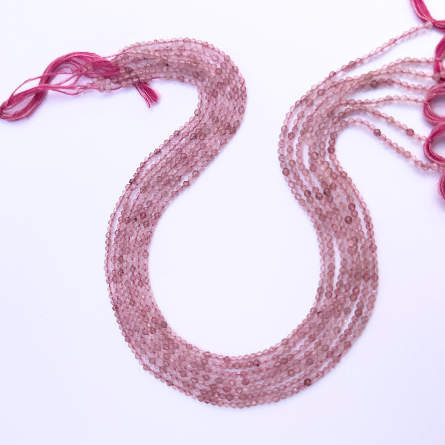 Close-up of Strawberry Quartz gemstone beads showing faceted rondelle cut and sparkle.