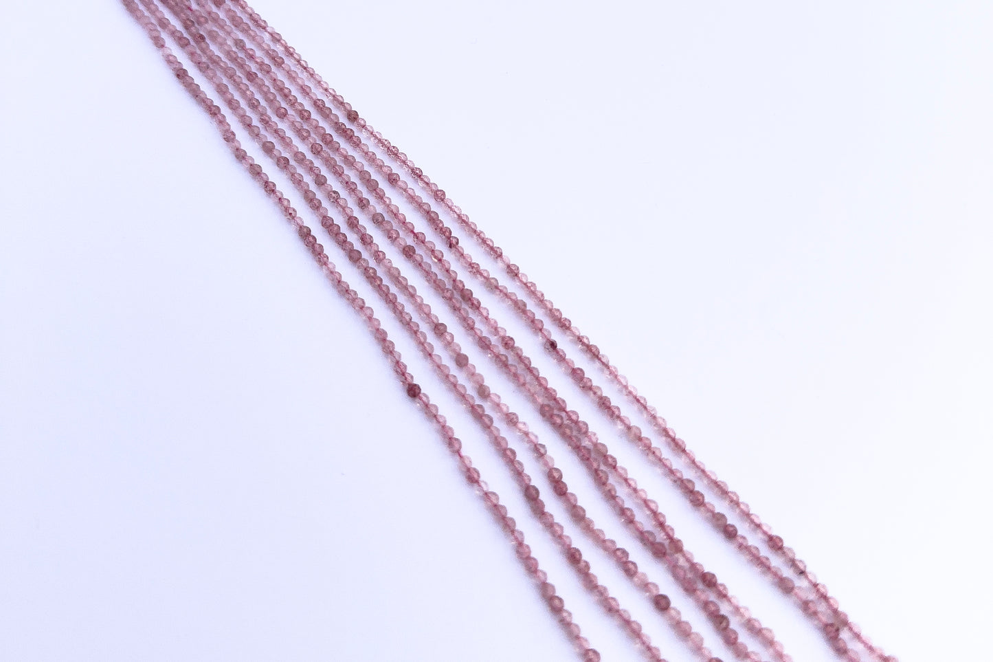 Stone beads in Strawberry Quartz finish laid flat to highlight their 2.5mm size and faceting.