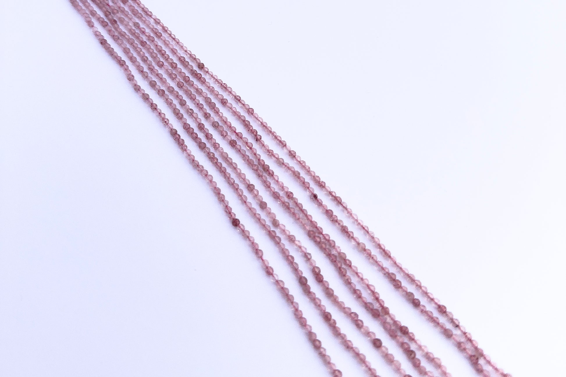 Stone beads in Strawberry Quartz finish laid flat to highlight their 2.5mm size and faceting.